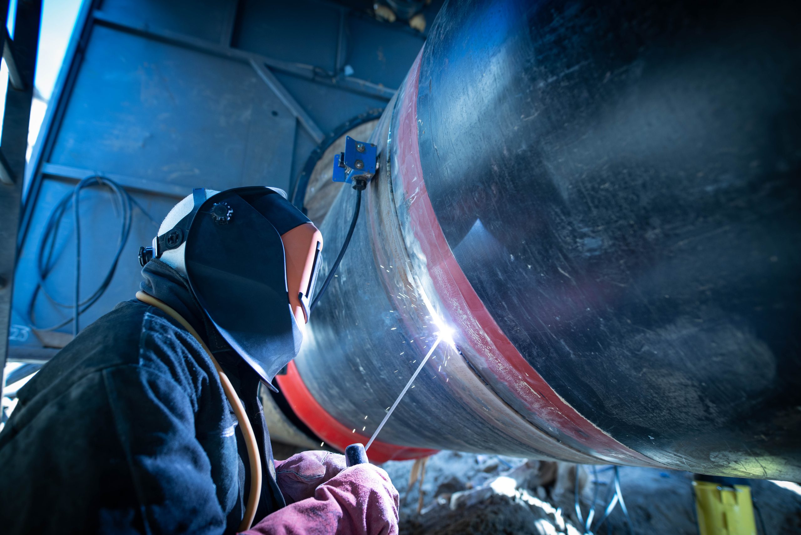 Professional welder welding pipe on a pipeline construction. Professional welder welding pipe on a pipeline construction.
